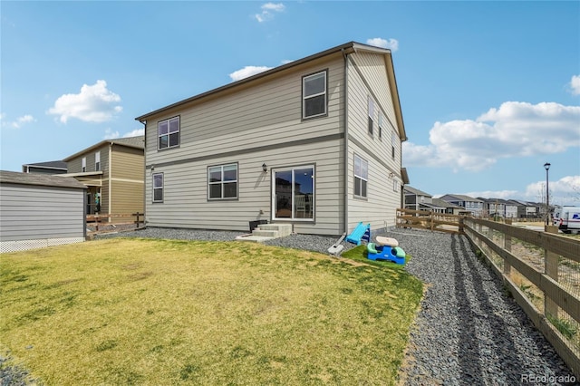 rear view of property with entry steps, fence, and a lawn