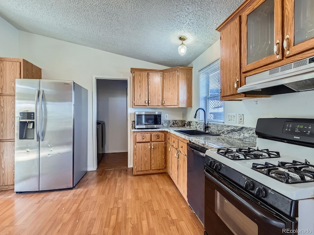 kitchen featuring vaulted ceiling, sink, stainless steel appliances, a textured ceiling, and light hardwood / wood-style flooring