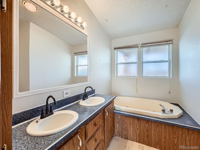 bathroom with vanity, vaulted ceiling, a bath, and a textured ceiling