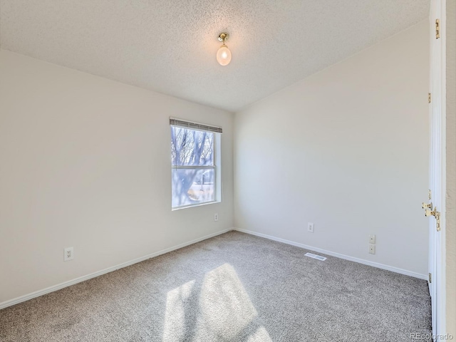 spare room featuring lofted ceiling, carpet flooring, and a textured ceiling