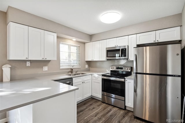 kitchen with sink, appliances with stainless steel finishes, dark wood-type flooring, and white cabinetry