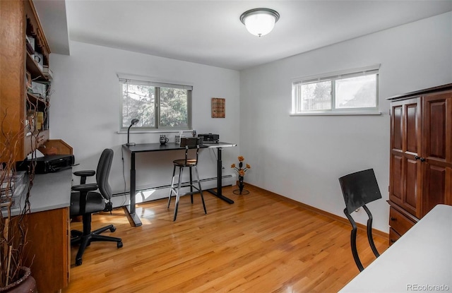 office space featuring a baseboard heating unit, plenty of natural light, and light hardwood / wood-style floors