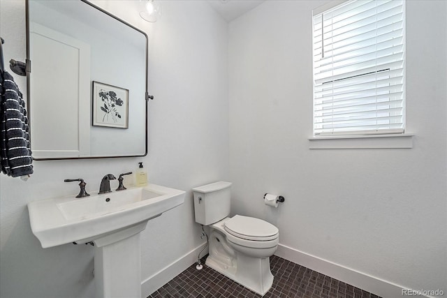 bathroom with toilet, sink, and tile patterned flooring