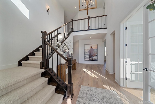 entryway featuring a notable chandelier, light wood-type flooring, high vaulted ceiling, and a skylight