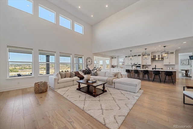 living room with a towering ceiling, light wood-type flooring, and a healthy amount of sunlight