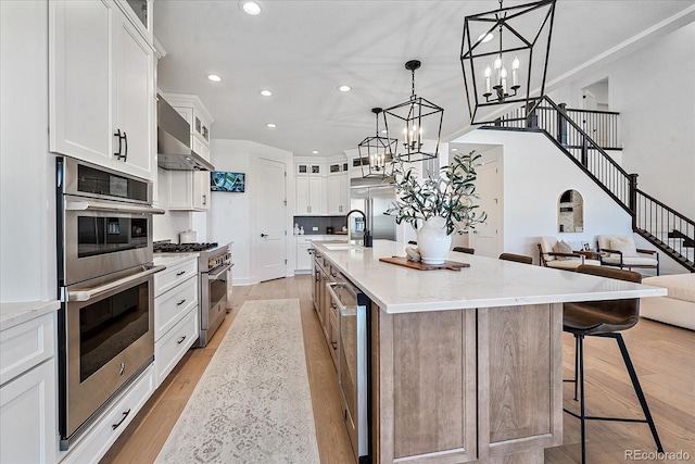 kitchen featuring a spacious island, white cabinetry, appliances with stainless steel finishes, and hanging light fixtures