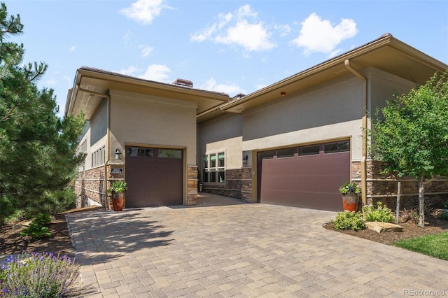 10243 Spring Green Dr, Englewood, CO 80112 - view of front of house with stucco siding, an attached garage, stone siding, and decorative driveway