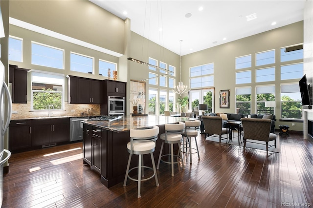 10243 Spring Green Dr, Englewood, CO 80112 - kitchen featuring stainless steel appliances, open floor plan, a high ceiling, stone counters, and a breakfast bar area
