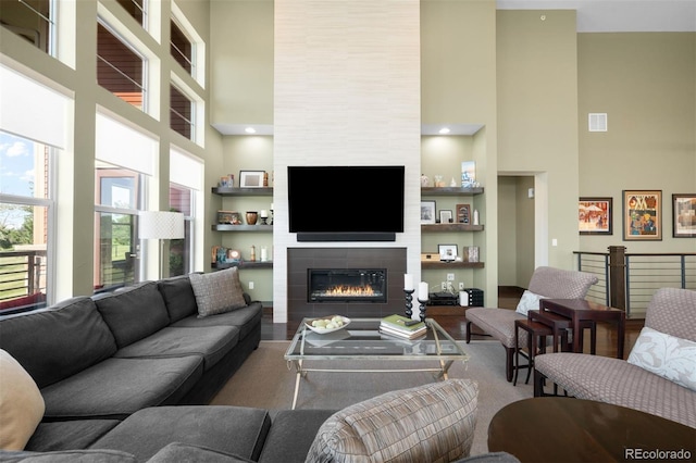 10243 Spring Green Dr, Englewood, CO 80112 - living area featuring a towering ceiling, a tile fireplace, built in shelves, and wood finished floors