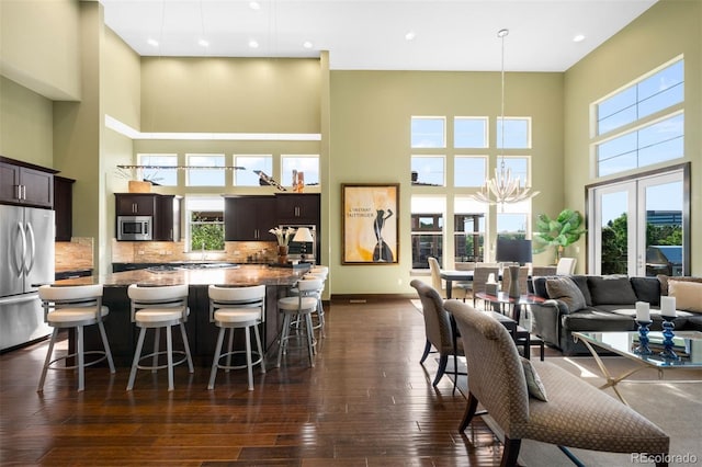 10243 Spring Green Dr, Englewood, CO 80112 - kitchen featuring stainless steel appliances, a high ceiling, a center island, a breakfast bar, and dark wood finished floors