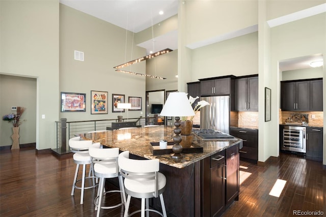 10243 Spring Green Dr, Englewood, CO 80112 - kitchen with a high ceiling, beverage cooler, stainless steel appliances, dark wood-style flooring, and a breakfast bar