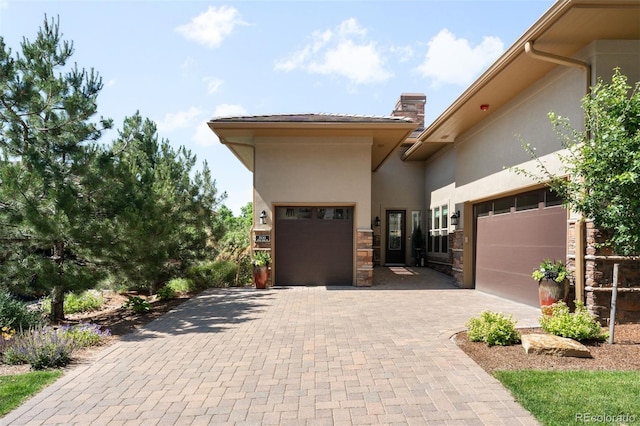 10243 Spring Green Dr, Englewood, CO 80112 - view of front facade with stucco siding, a garage, decorative driveway, a chimney, and stone siding