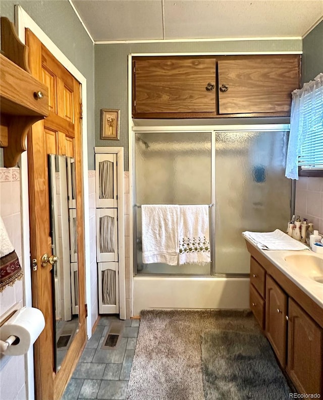 647 D St, Salida, CO 81201 - full bathroom with bath / shower combo with glass door, vanity, ornamental molding, stone finish floors, and tile walls