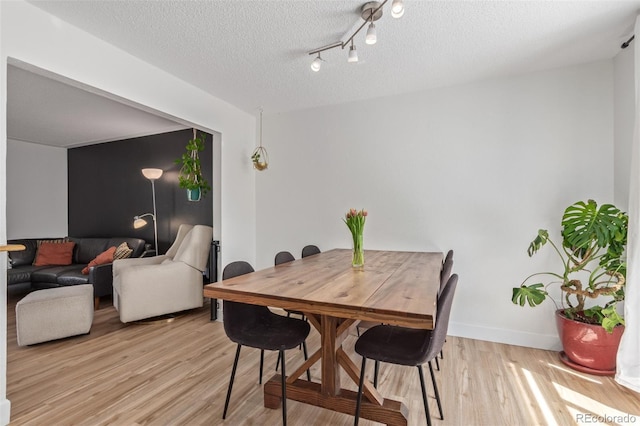 4808 S Ward Way, Morrison, CO 80465 - dining room with light wood-style flooring, a textured ceiling, and baseboards