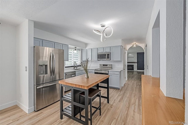 4808 S Ward Way, Morrison, CO 80465 - kitchen with stainless steel appliances, arched walkways, gray cabinetry, light countertops, and light wood finished floors