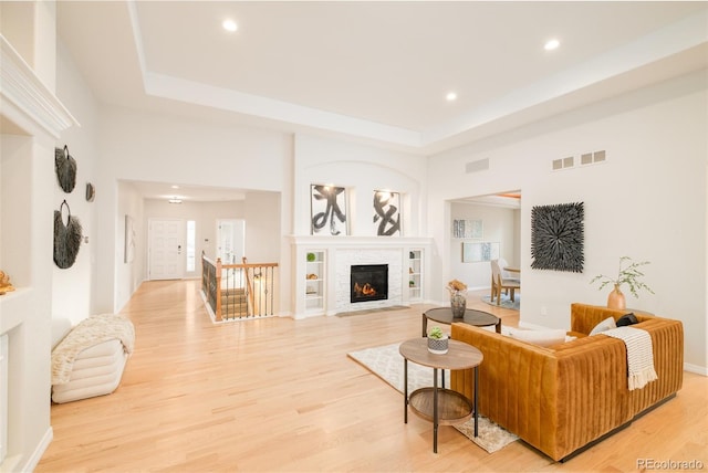 living room featuring a tray ceiling, hardwood / wood-style flooring, and built in features