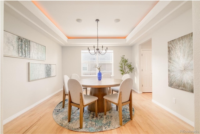 dining space featuring an inviting chandelier, a tray ceiling, and hardwood / wood-style floors