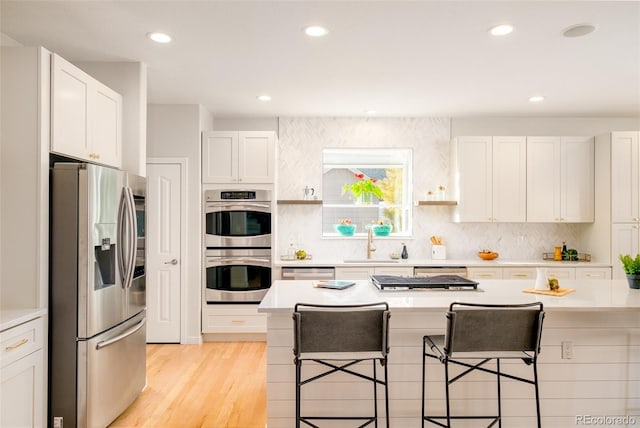 kitchen featuring sink, a breakfast bar, appliances with stainless steel finishes, a center island, and white cabinets