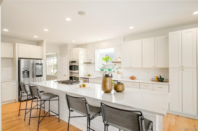 kitchen with a breakfast bar, white cabinets, and appliances with stainless steel finishes