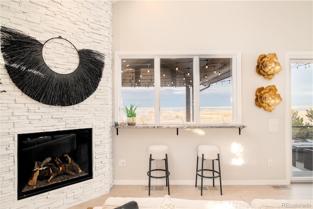 living room with a stone fireplace and light wood-type flooring