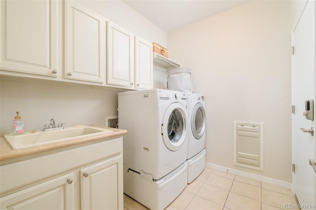 washroom with sink, light tile patterned floors, washer and clothes dryer, and cabinets