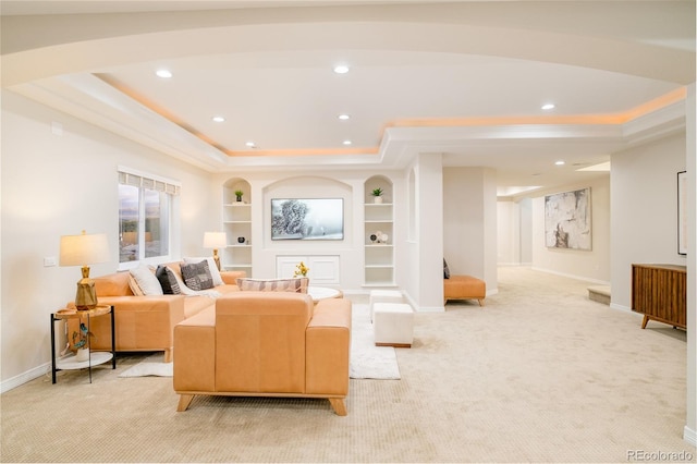 living room with a tray ceiling, built in features, and light colored carpet