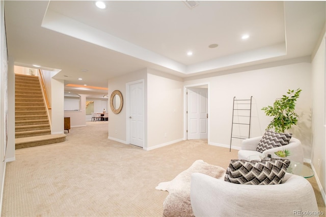 sitting room featuring a raised ceiling and light colored carpet