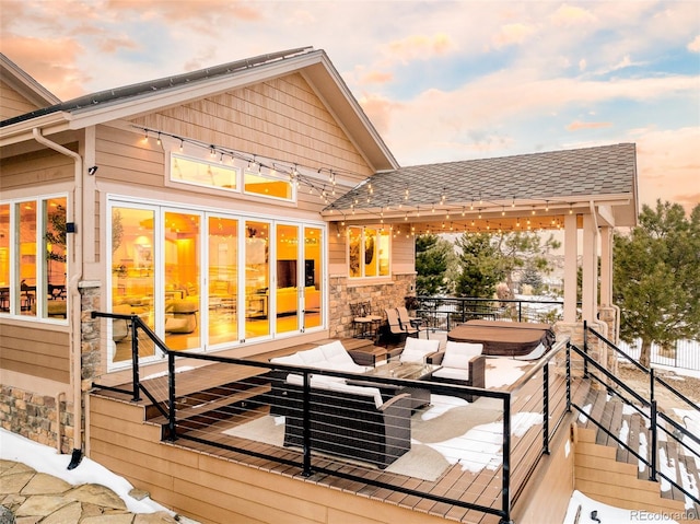 deck at dusk featuring a hot tub