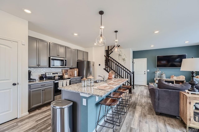 kitchen featuring stainless steel appliances, decorative light fixtures, light wood-type flooring, and gray cabinets