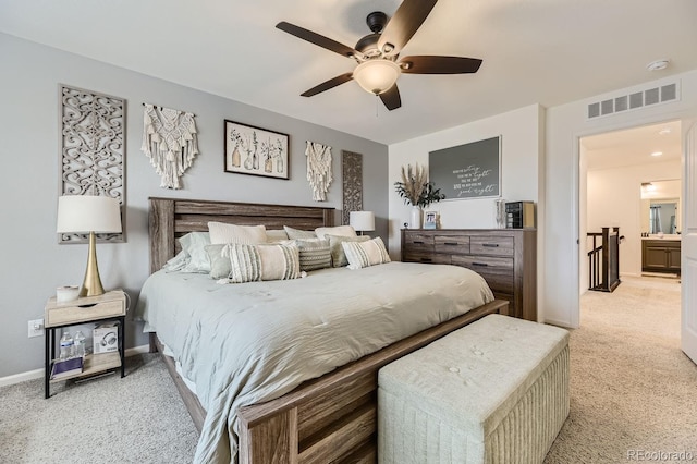 bedroom with ceiling fan, ensuite bathroom, and light colored carpet