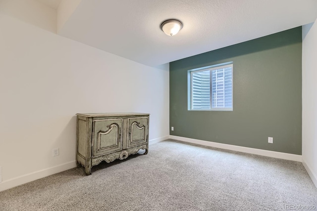 unfurnished room featuring a textured ceiling and light colored carpet