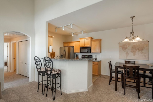 kitchen with black appliances, a chandelier, track lighting, and light colored carpet