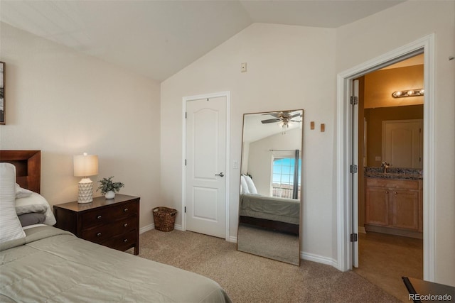 carpeted bedroom with ensuite bathroom, sink, and vaulted ceiling