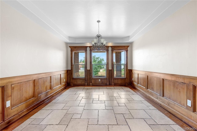 1195 W 70th Ave, Denver, CO 80221 - unfurnished dining area with a chandelier, a wainscoted wall, stone tile floors, and a raised ceiling