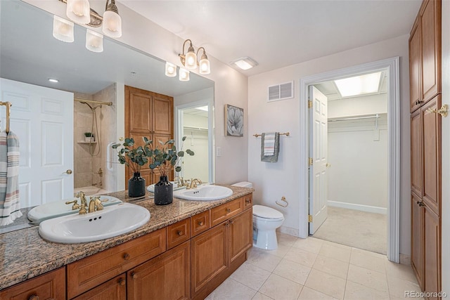 full bath featuring toilet, a sink, visible vents, and a walk in closet