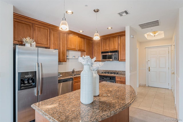 kitchen with appliances with stainless steel finishes, a center island, visible vents, and dark stone counters