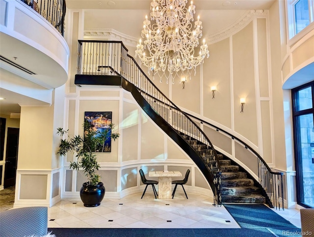 stairs featuring a high ceiling, a decorative wall, a notable chandelier, and tile patterned floors