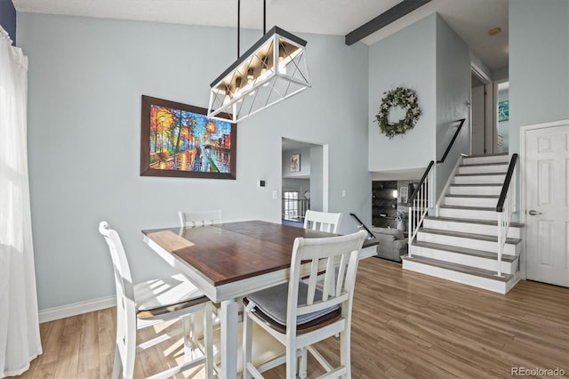 8815 W Quarto Cir, Littleton, CO 80128 - dining area with stairs, wood finished floors, baseboards, a chandelier, and high vaulted ceiling
