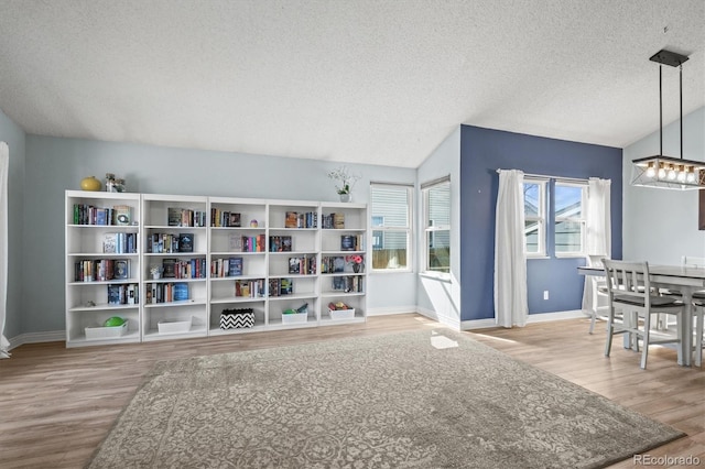 8815 W Quarto Cir, Littleton, CO 80128 - sitting room featuring a textured ceiling, wood finished floors, baseboards, and lofted ceiling