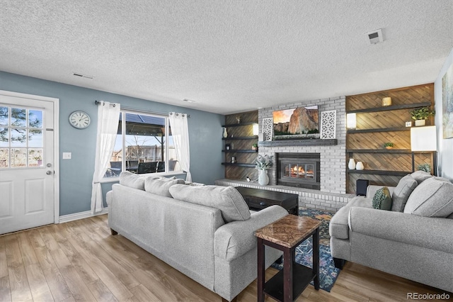 8815 W Quarto Cir, Littleton, CO 80128 - living room featuring light wood finished floors, a fireplace, baseboards, and a textured ceiling