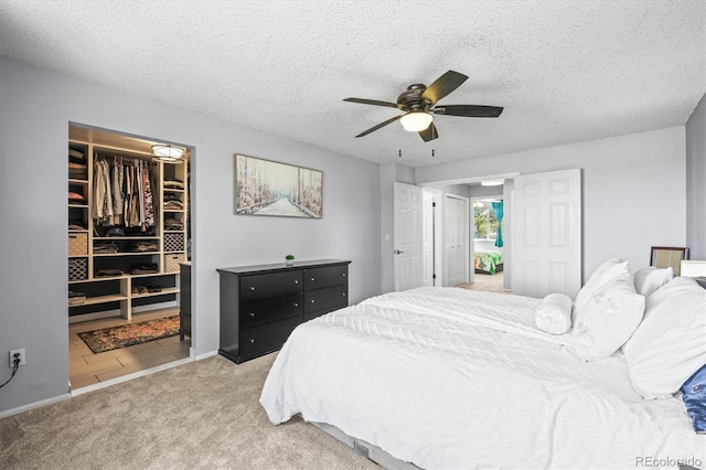 8815 W Quarto Cir, Littleton, CO 80128 - bedroom featuring light carpet, a walk in closet, a closet, a ceiling fan, and a textured ceiling