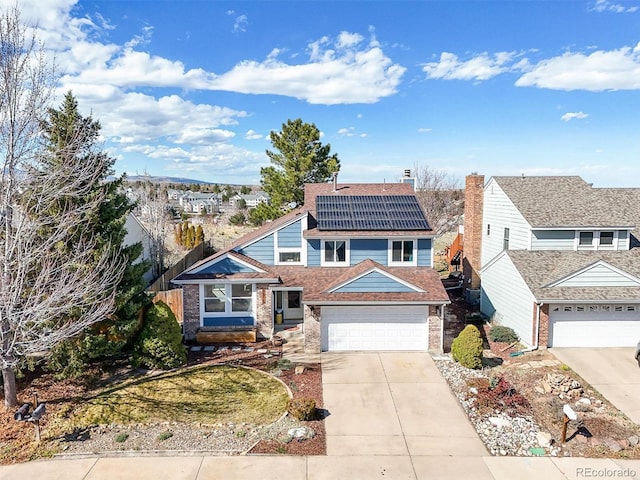 8815 W Quarto Cir, Littleton, CO 80128 - view of front of house with driveway, roof mounted solar panels, fence, a garage, and roof with shingles
