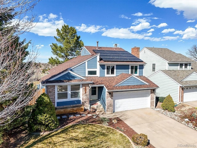 8815 W Quarto Cir, Littleton, CO 80128 - view of front of property featuring roof mounted solar panels, driveway, roof with shingles, an attached garage, and a chimney