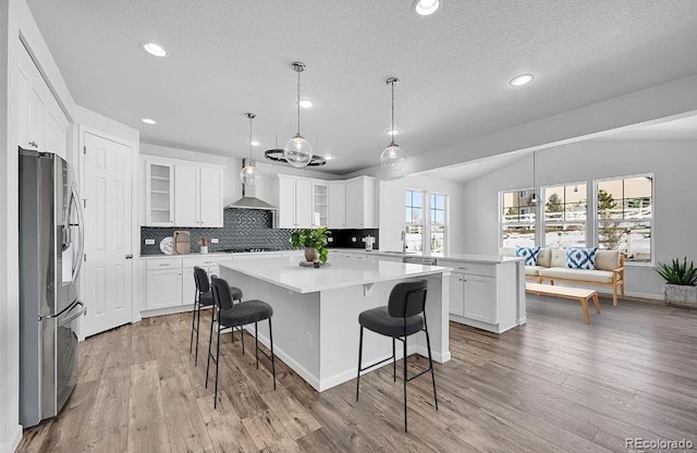 kitchen with stainless steel refrigerator with ice dispenser, a kitchen bar, a center island, and white cabinets