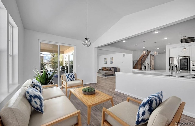 living room featuring lofted ceiling, sink, and wood-type flooring