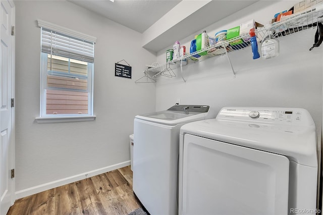 clothes washing area with plenty of natural light, washing machine and dryer, and light hardwood / wood-style floors