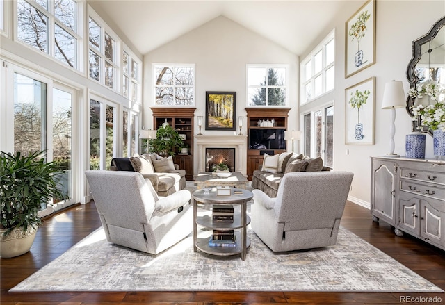 4483 W Cottonwood Pl, Littleton, CO 80123 - living room featuring high vaulted ceiling, dark wood-style flooring, a lit fireplace, and baseboards