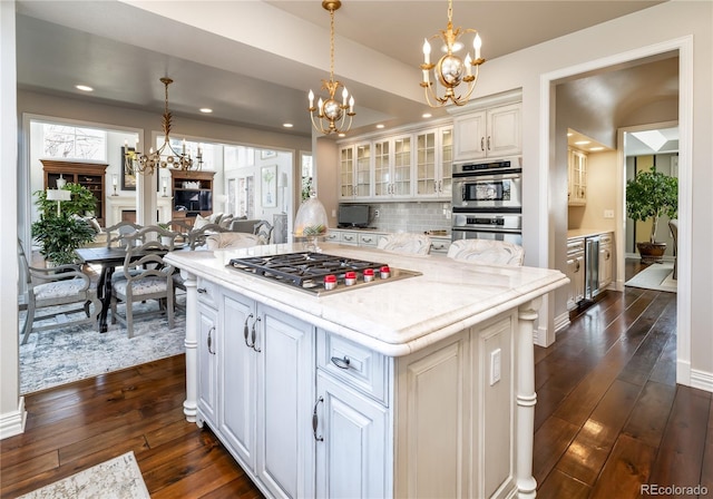 4483 W Cottonwood Pl, Littleton, CO 80123 - kitchen with appliances with stainless steel finishes, a chandelier, wine cooler, dark wood-style flooring, and decorative backsplash