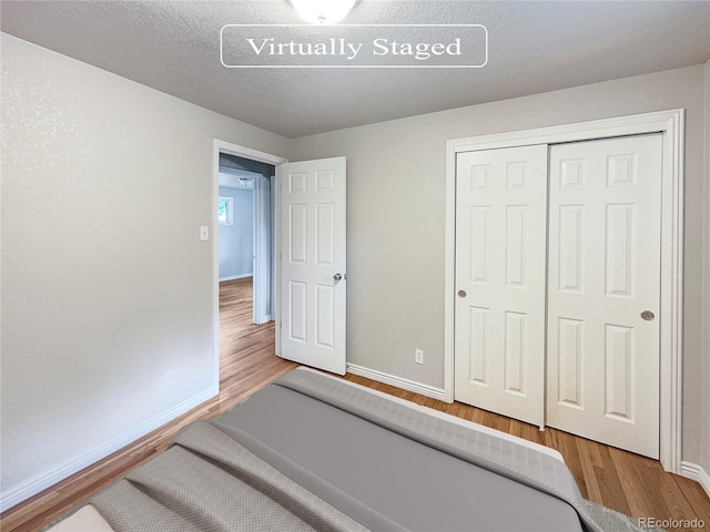 bedroom with a closet, hardwood / wood-style floors, and a textured ceiling