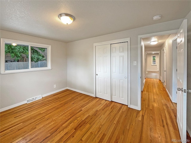 unfurnished bedroom featuring a closet, light hardwood / wood-style floors, and a textured ceiling